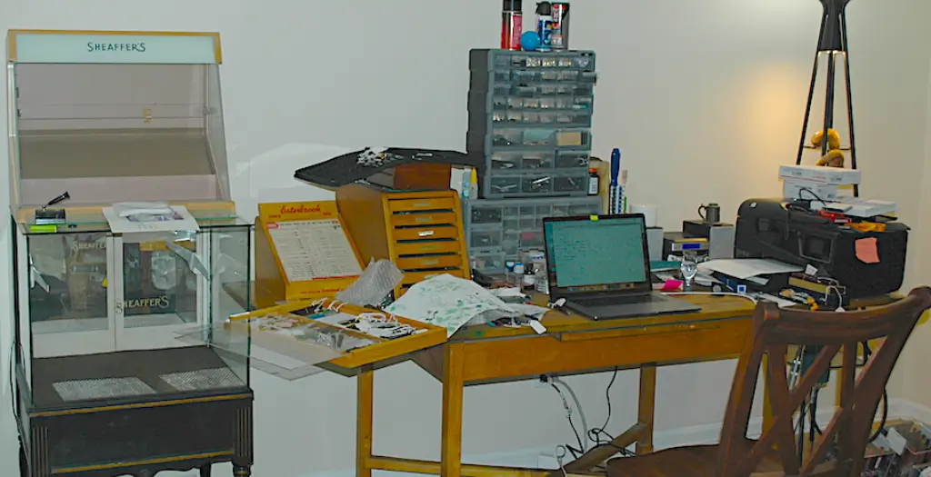 Cluttered desk with laptop and various items.